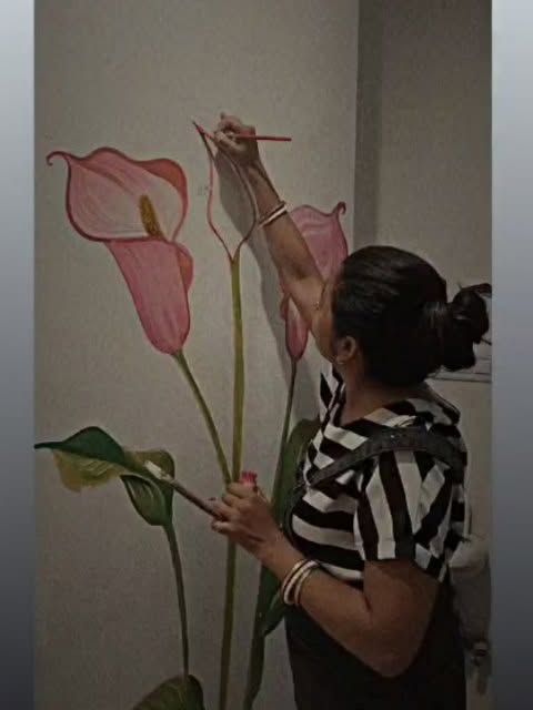 Supi painting a pink calla lily mural by hand